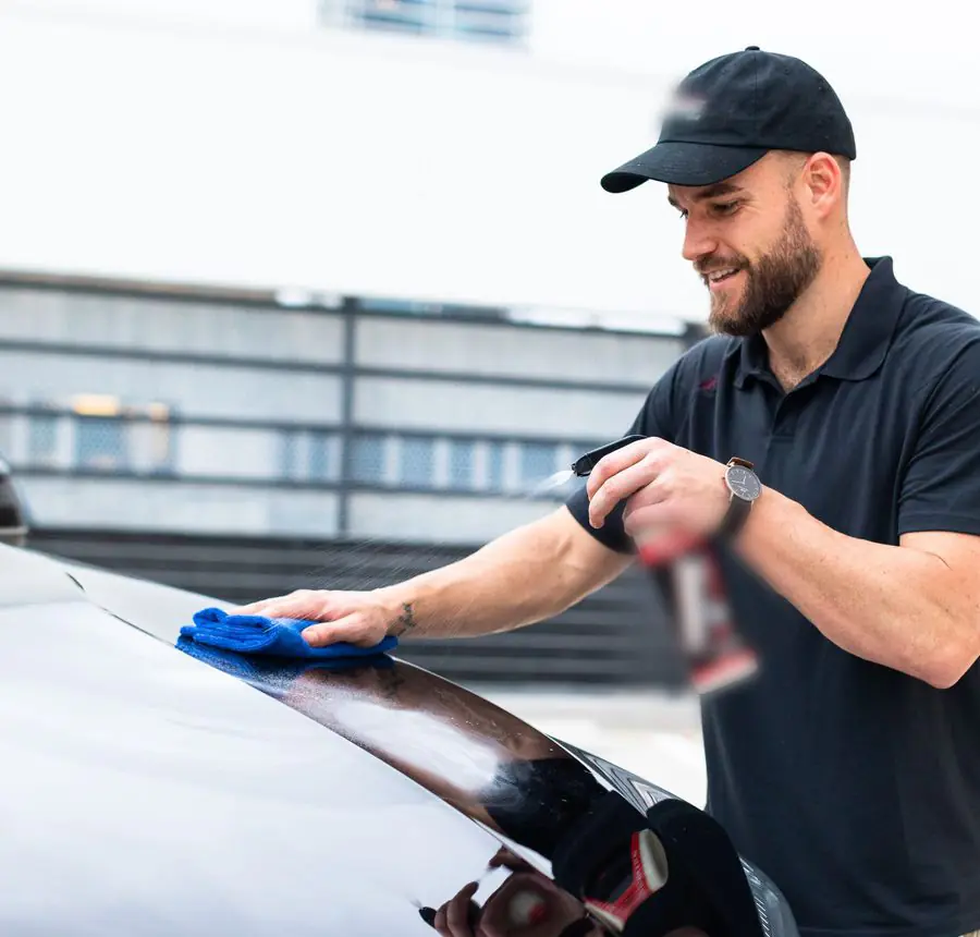 A detailer in uniform drying a clean car